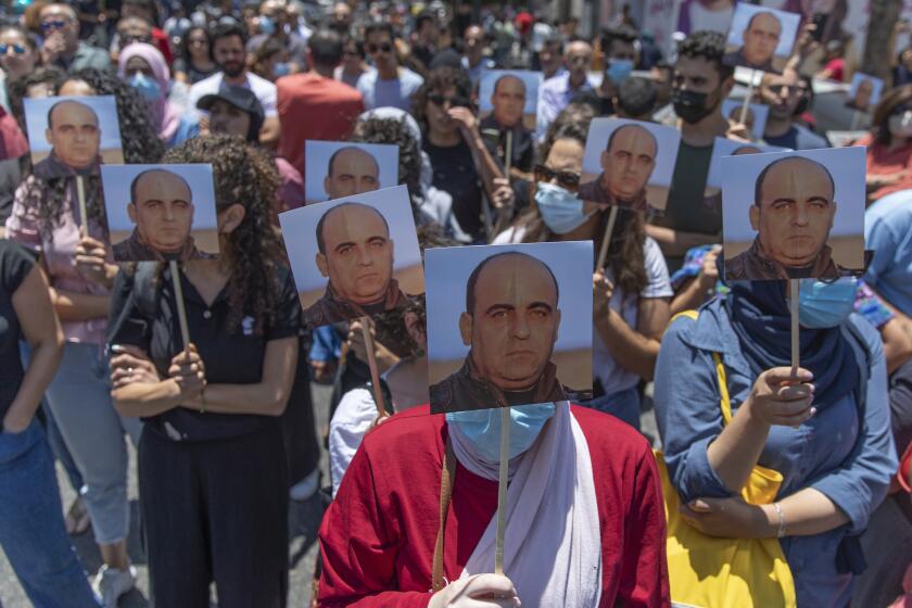Angry demonstrators carry pictures of Nizar Banat, an outspoken critic of the Palestinian Authority, and chant anti-PA slogans during a rally protesting his death, in the West Bank city of Ramallah, Thursday, June 24, 2021. Banat who was a candidate in parliamentary elections called off earlier this year died after Palestinian security forces arrested him and beat him with batons on Thursday, his family said. (AP Photo/Nasser Nasser)
