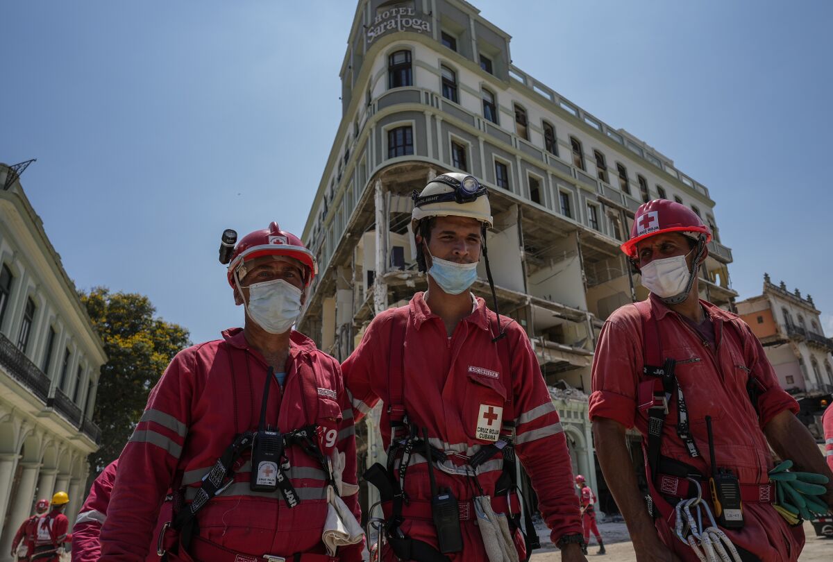 Cuban Red Cross workers walk away from the destroyed five-star Hotel Saratoga after searching through the rubble days after a deadly explosion in Old Havana, Cuba, Tuesday, May 10, 2022. An apparent gas leak ignited on Friday, May 6. (AP Photo/Ramon Espinosa)