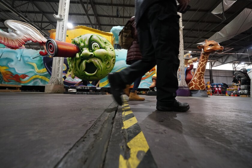 People walk past parts of Mardi Gras floats past and present, at Mardi Gras World, where Kern Studios creates and stores some of their floats, in New Orleans, Friday, Feb. 12, 2021. New Orleans' annual pre-Lenten Mardi Gras celebration is muted this year because of the coronavirus pandemic. Parades canceled. Bars closed. Crowds suppressed. Mardi Gras joy is muted this year in New Orleans as authorities seek to stifle the coronavirus's spread. And it's a blow to the tradition-bound city's party-loving soul. (AP Photo/Gerald Herbert)