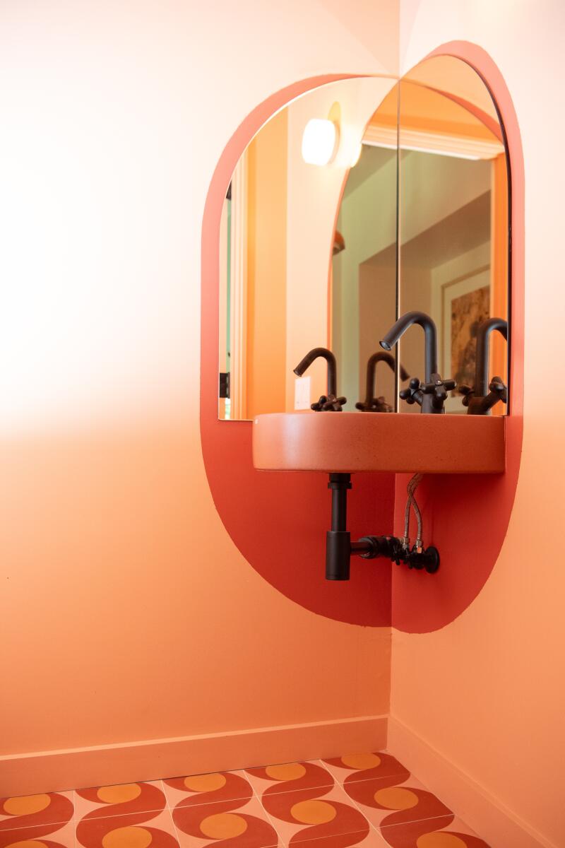 A powder room sink with rust and coral tile