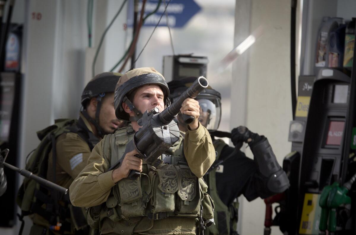 An Israeli soldier fires a tear gas canister during clashes with Palestinian protesters near Ramallah, West Bank.