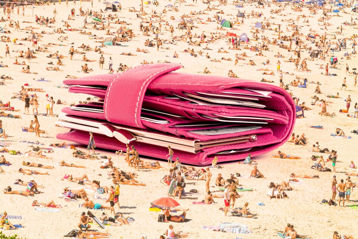 Photo illustration of a giant wallet on a beach with sunbathers.