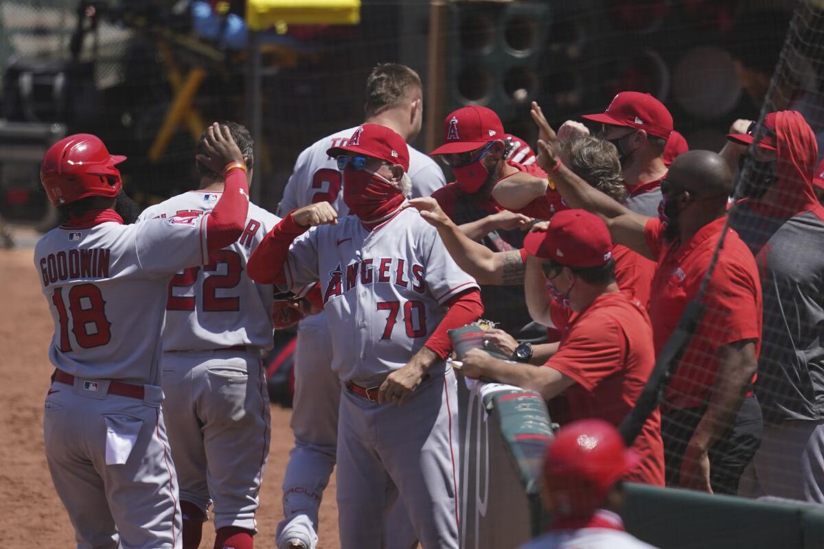 Angels manager Joe Maddon, center, greets players after a three-run home run by Mike Trout.