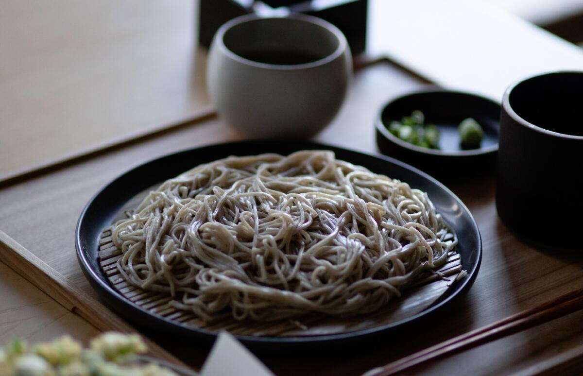 A black plate piled with soba noodles