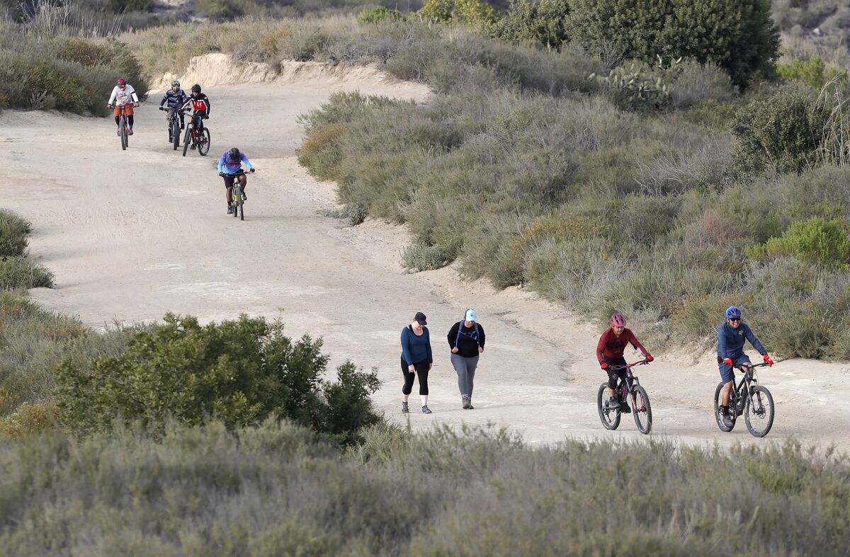 Mountain bikers and hikers climb a well-known trail at Top of the World in Laguna Beach on a recent afternoon.