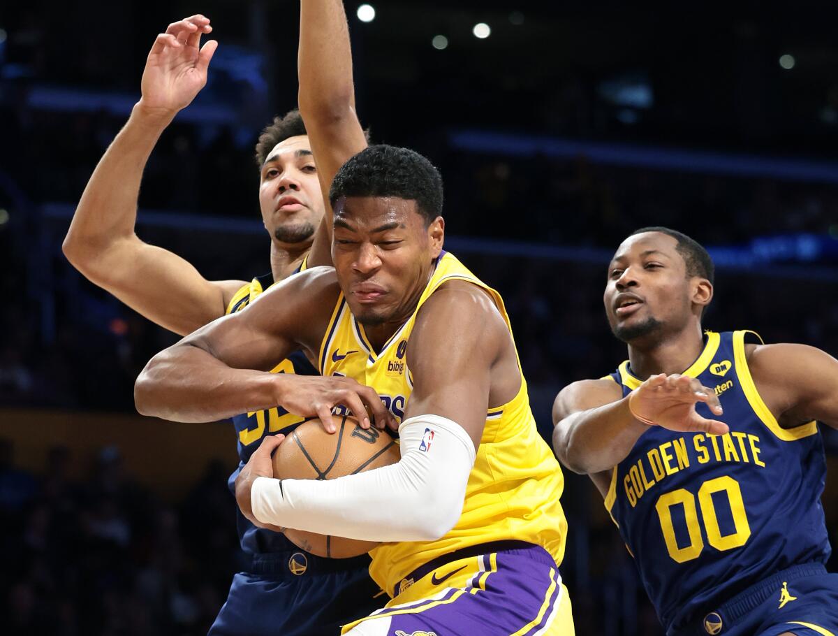Lakers forward Rui Hachimura, center, grabs a rebound from the Warriors' Trayce Jackson-Davis, left, and Jonathan Kuminga.