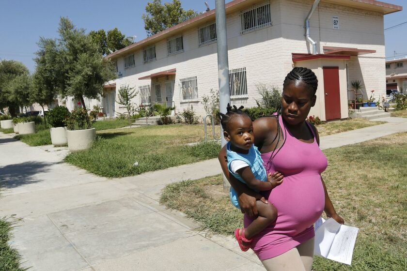 BOYLE HEIGHTS, CA-JULY 7, 2016: Jasmond, 25 (didn't want last name used) and her daughter Jahkeel, 1 and 1/2, make their way to their home in Ramona Gardens housing project in Boyle Heights on July 7, 2016. Jasmond said that she has lived their for the past 2 years, but her parents, who she now lives with, have been there for the past 9 years. A federal grand jury has indicted seen Latino gang members in connection with a 2014 firebombing attack at Ramona Gardens housing project, accusing them of trying to drive black residents out of the neighborhood, prosecutors announced Thursday. (Mel Melcon/Los Angeles Times)