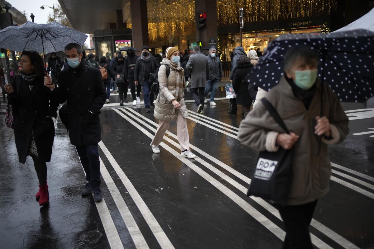 Unas personas con cubrebocas por el coronavirus caminan por una calle de París
