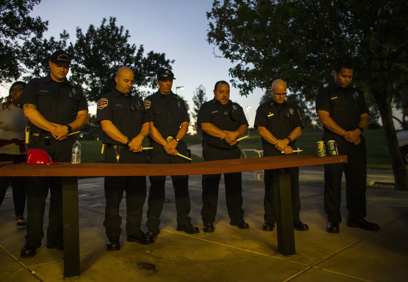Firefighters and paramedics bow their heads in prayer during a vigil for the victims of the mass shooting at Mountain Crest Park in Las Vegas.