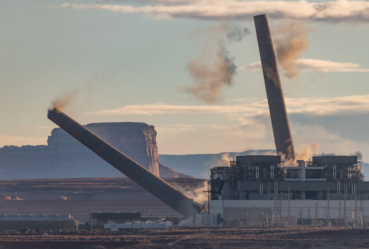 Two of the three smokestacks at Navajo Generating Station outside Page, Ariz., come tumbling down on Dec. 18, 2020.