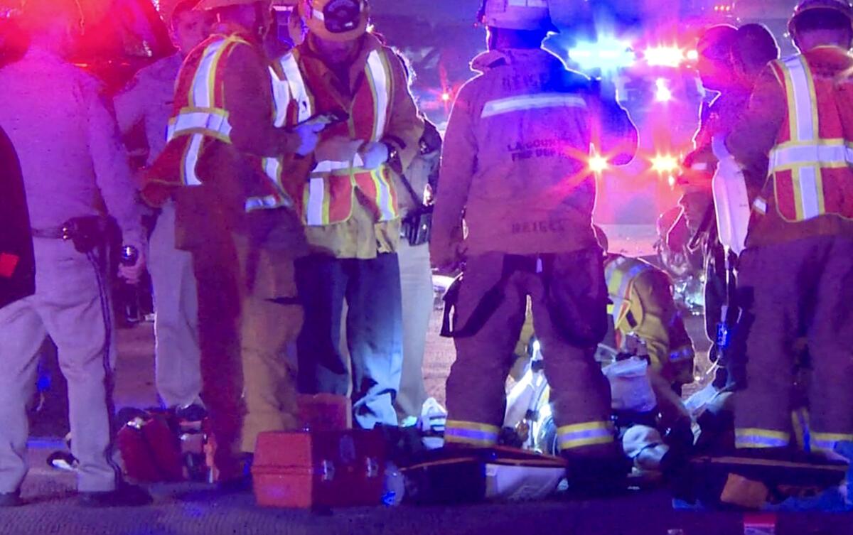 People in reflective vests and police uniforms surround a stretcher on a freeway.