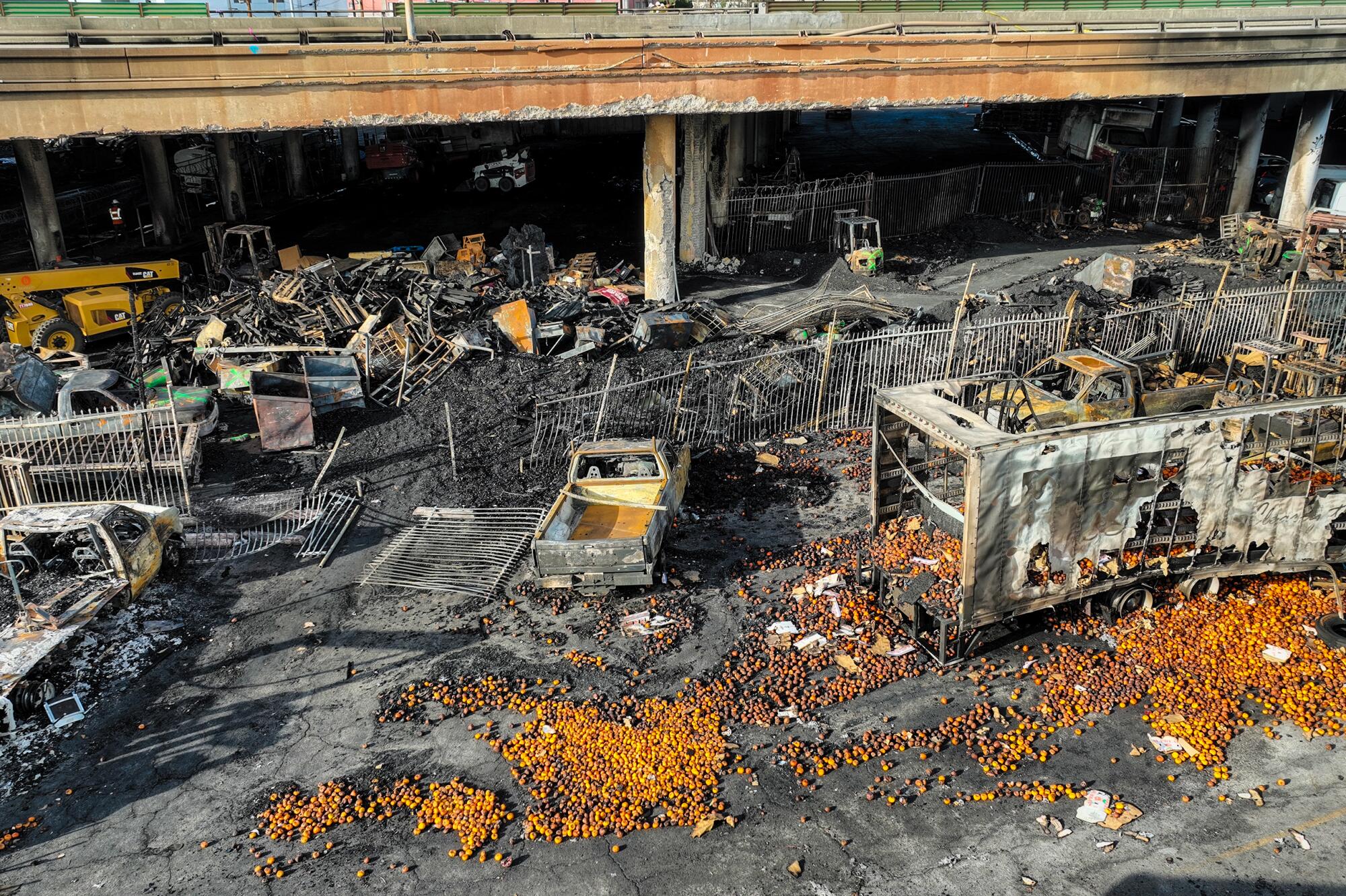 Scattered produce, the shells of burned trucks and a pile of charred debris next to an elevated freeway.