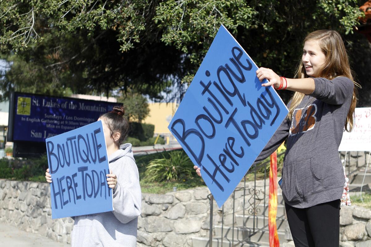 Lizzy Brookey, left, and Emma Kupershmidt, both 14, hold up signs for the Crescenta Valley High School Prom Plus fundraising boutique at St. Luke's of the Mountains Episcopal Church in La Crescenta on Saturday, Nov. 15, 2014.