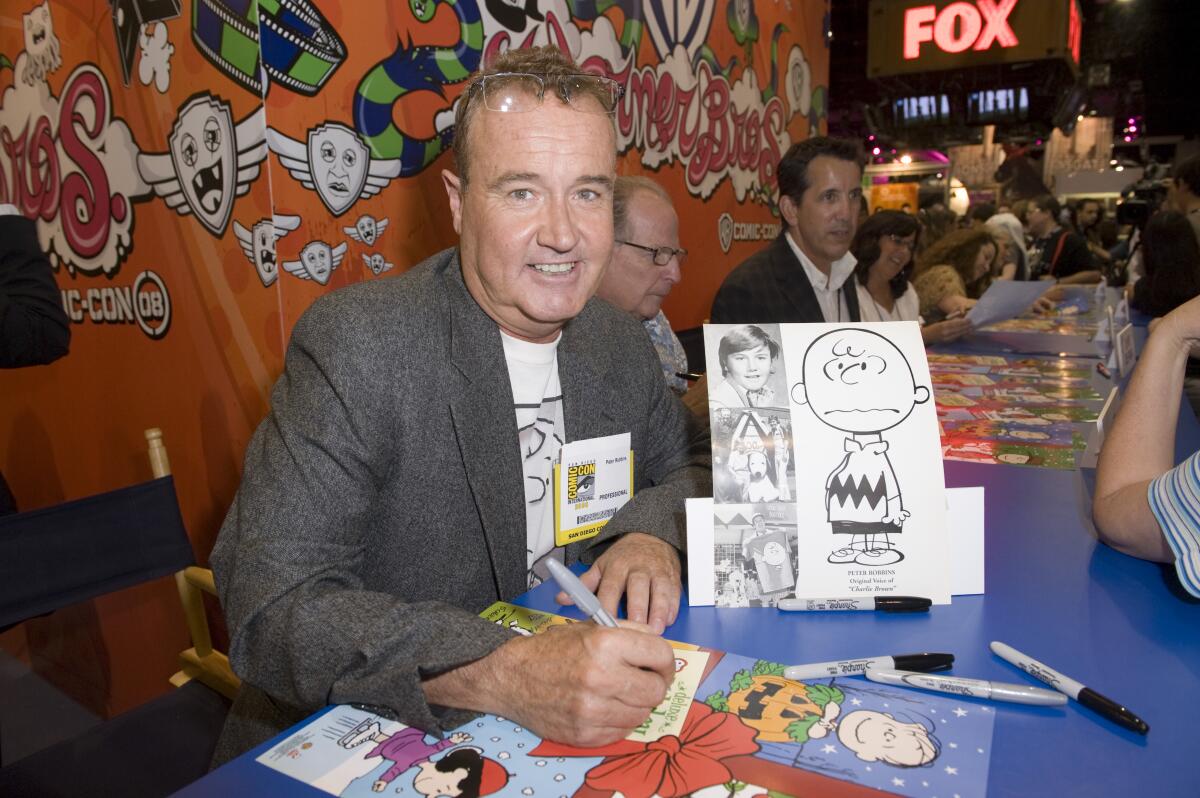 A man sits at a table signing autographs