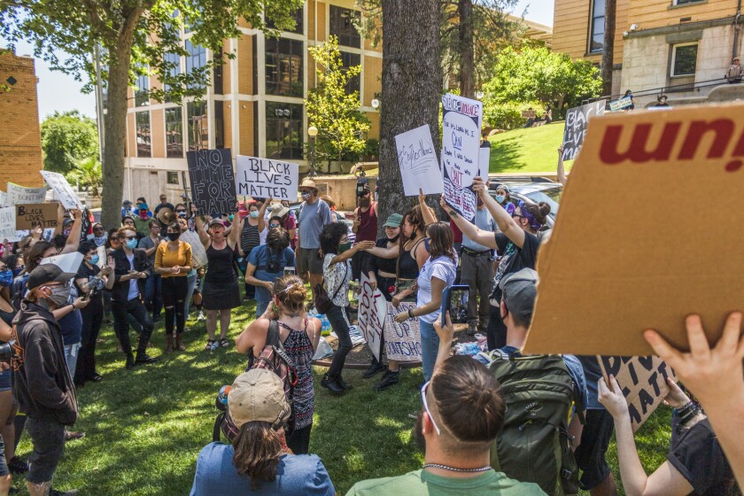 Back Lives Matter protesters look on as the day's key speakers embrace after address in Sonora, Calif.