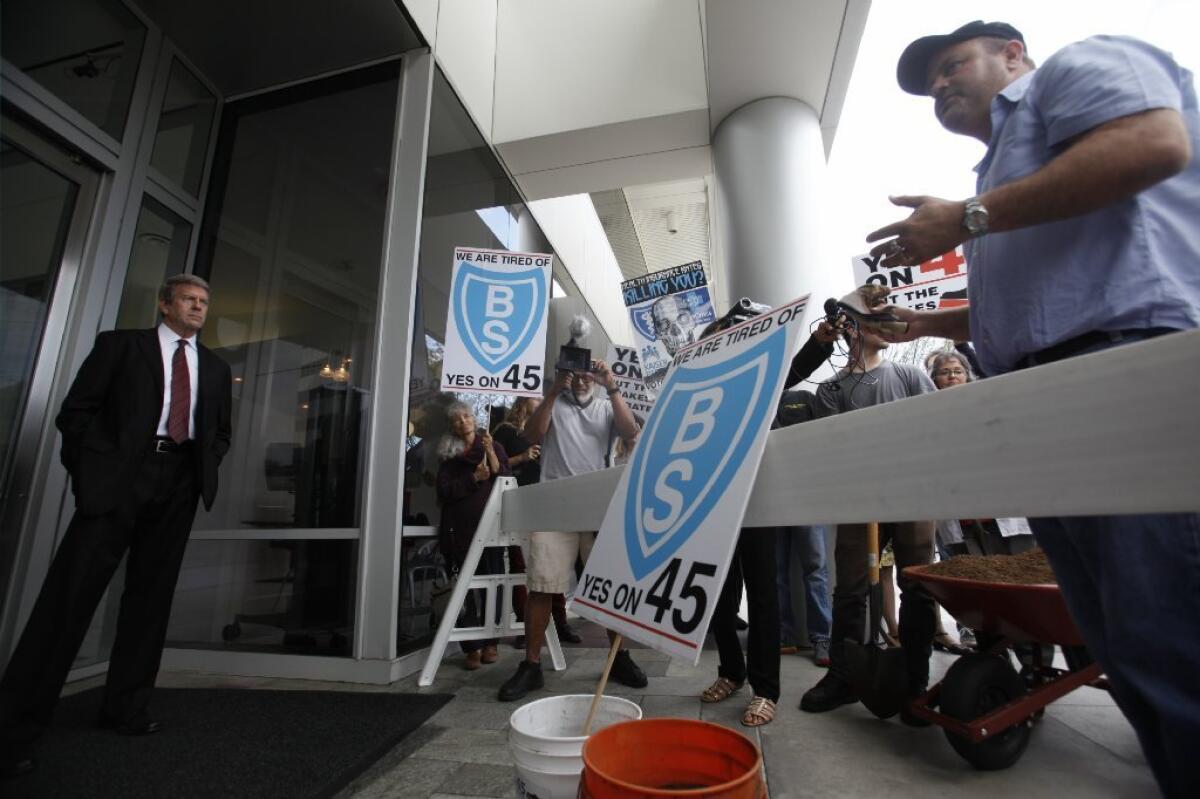 Consumers protest against Blue Shield of California in October over its opposition to a rate-regulation ballot measure at the company's El Segundo office. On Monday, a former executive sued the insurer, alleging wrongful dismissal.