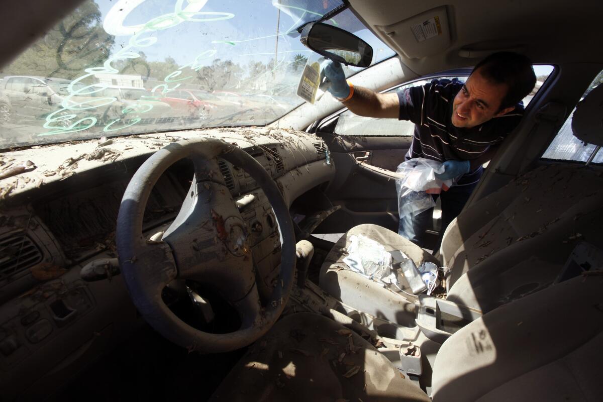 UCLA teacher Bobak Mortazavi salvages his parking pass from his flood-ravaged car in a parking lot behind Jackie Robinson Stadium on Tuesday.
