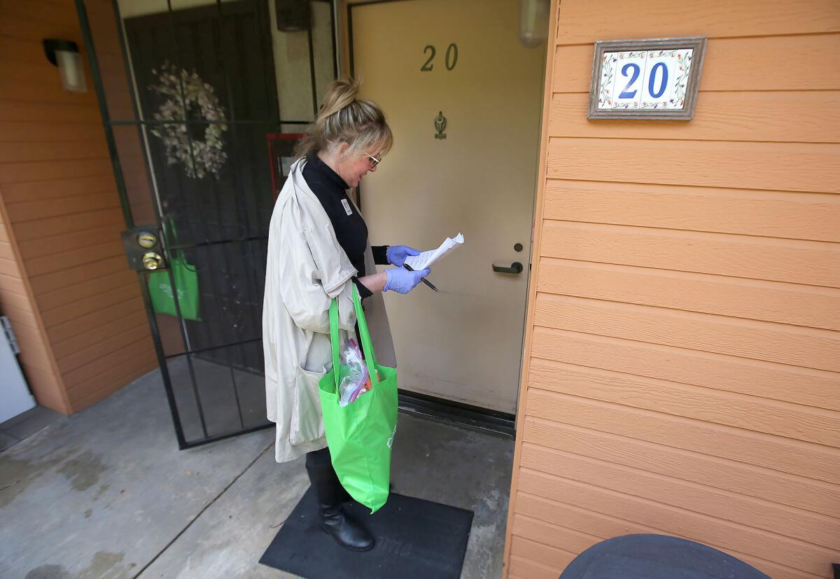 Rachael Berger, executive director of Sally's Fund, delivers a bag of groceries to a resident of the Vista Aliso senior apartments in Laguna Beach on Thursday.