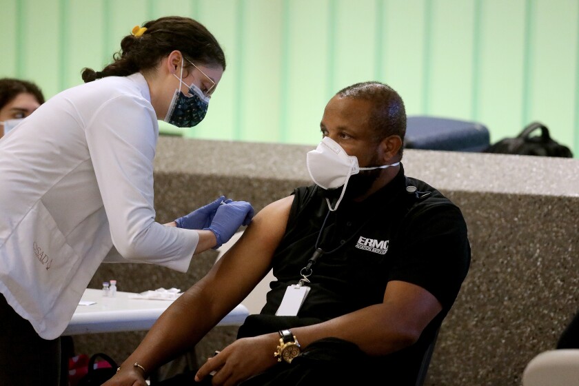 LOS ANGELES, CA - DECEMBER 22: Brendan (cq) Uzoagbado (cq), a worker at LAX, recieves a COVID-19 booster vaccination. Los Angeles International Airport (LAX) and the County of Los Angeles Public Health offer free, on-site COVID-19 vaccinations and booster shots to the public at Tom Bradley International Terminal (Terminal B) at LAX on Wednesday, Dec. 22, 2021 in Los Angeles, CA. Big jump in L.A. County COVID-19 Omicron varient cases heightens alarm about the unvaccinated. (Gary Coronado / Los Angeles Times)