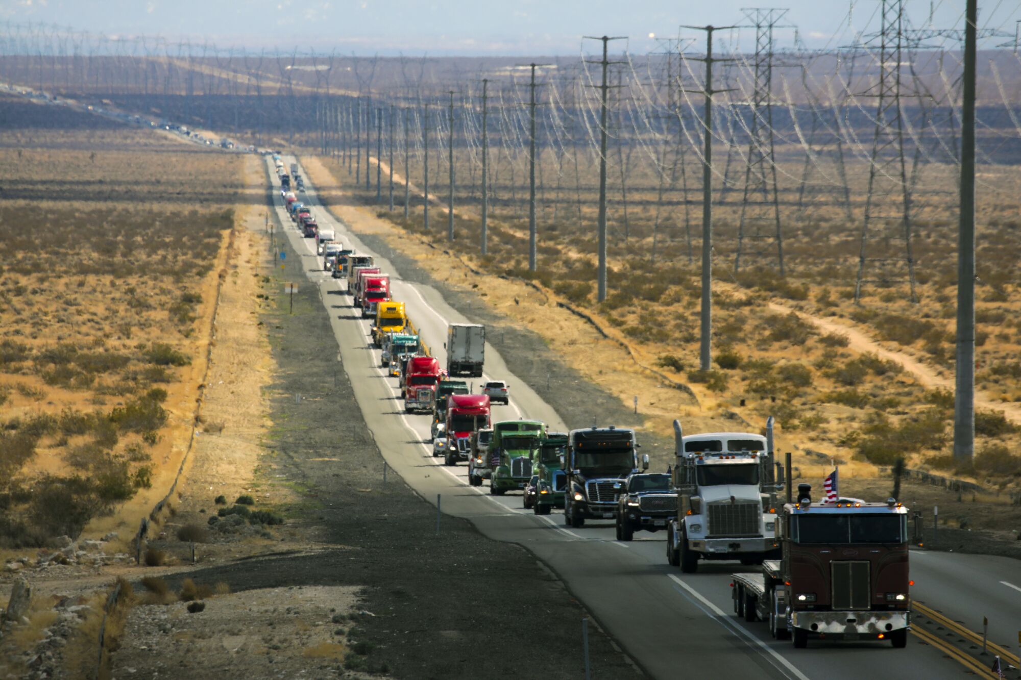 A line of big-rigs and other vehicles on a two-lane highway