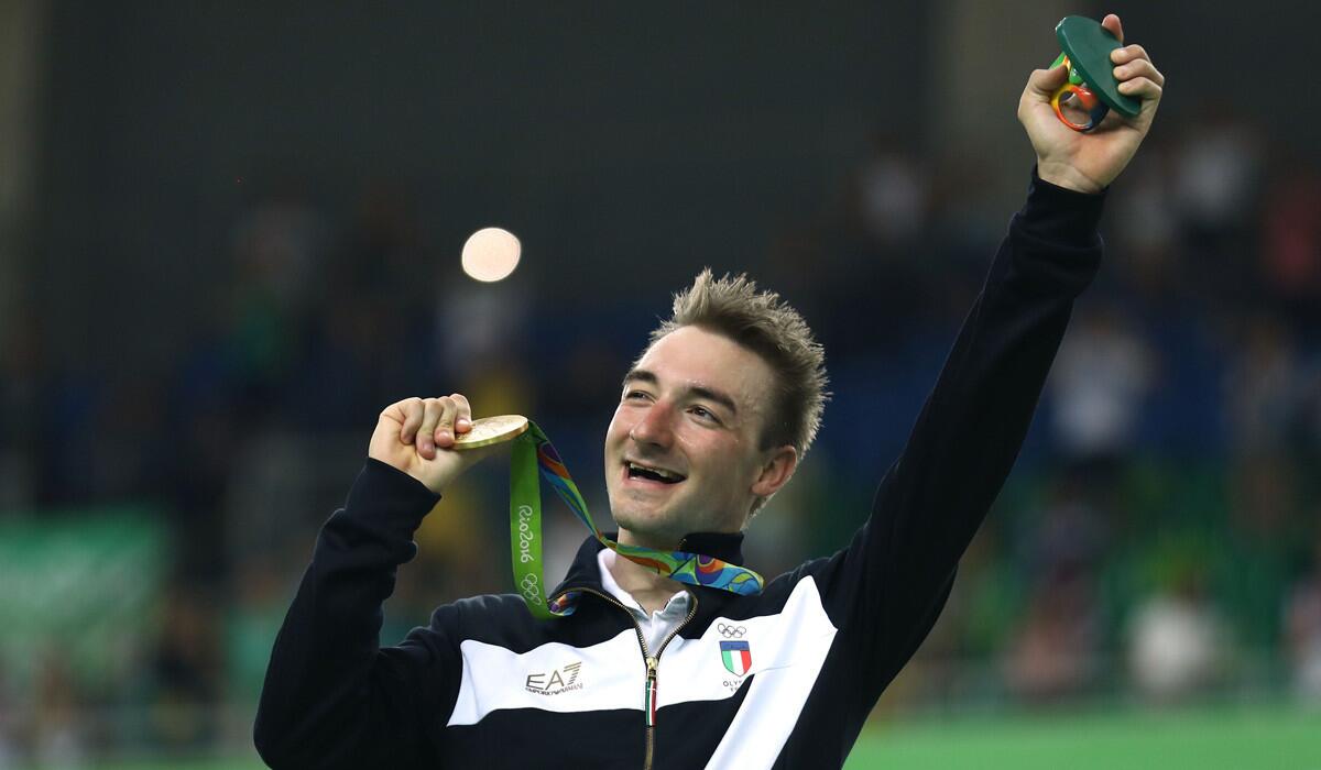 Elia Viviani of Italy holds the gold medal and Rio Olympics logo sculpture he received after his victory in a men's cycling competition Monday.
