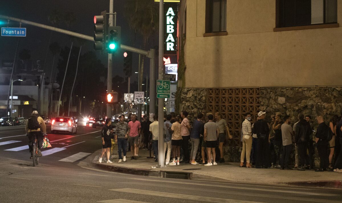 A line of people outside a bar.
