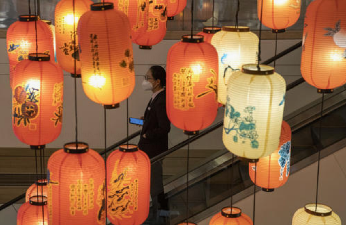 Un oficinista con mascarilla para protegerse contra el coronavirus pasa junto a una decoración con fearoles en un edificio comercial y de oficinas en Beijing, el jueves 19 de marzo de 2020. (AP Foto/Ng Han Guan)