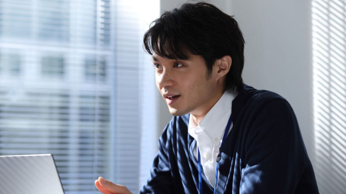A man in a sweater in a sleek, white, sunny space.