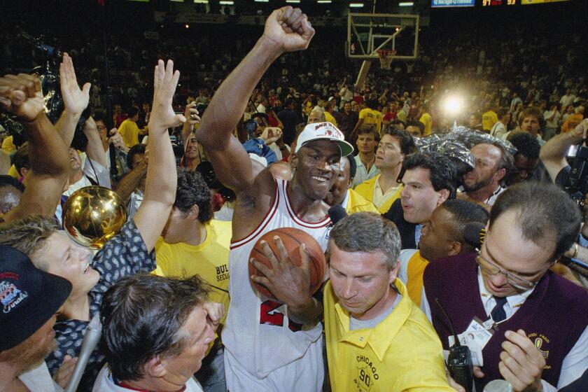 Chicago Bulls Michael Jordan is surrounded by fans as he is escorted from the floor of Chicago Stadium, Sunday, June 15, 1992. Jordan and his teammates returned to the floor after a locker room celebration following their NBA Championship win over the Portland Trail Blazers. (AP Photo/Mark Elias)