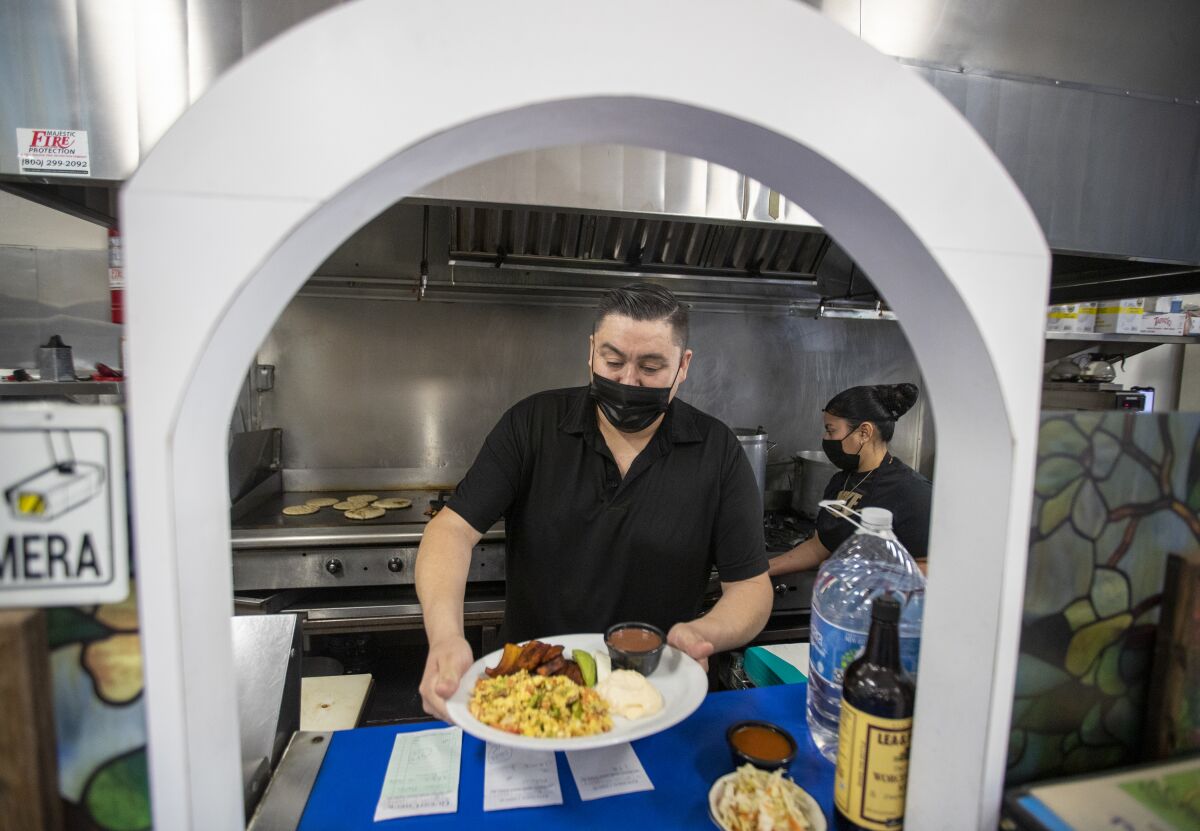 Alex Ramos serves a plate of food at a pupuseria.