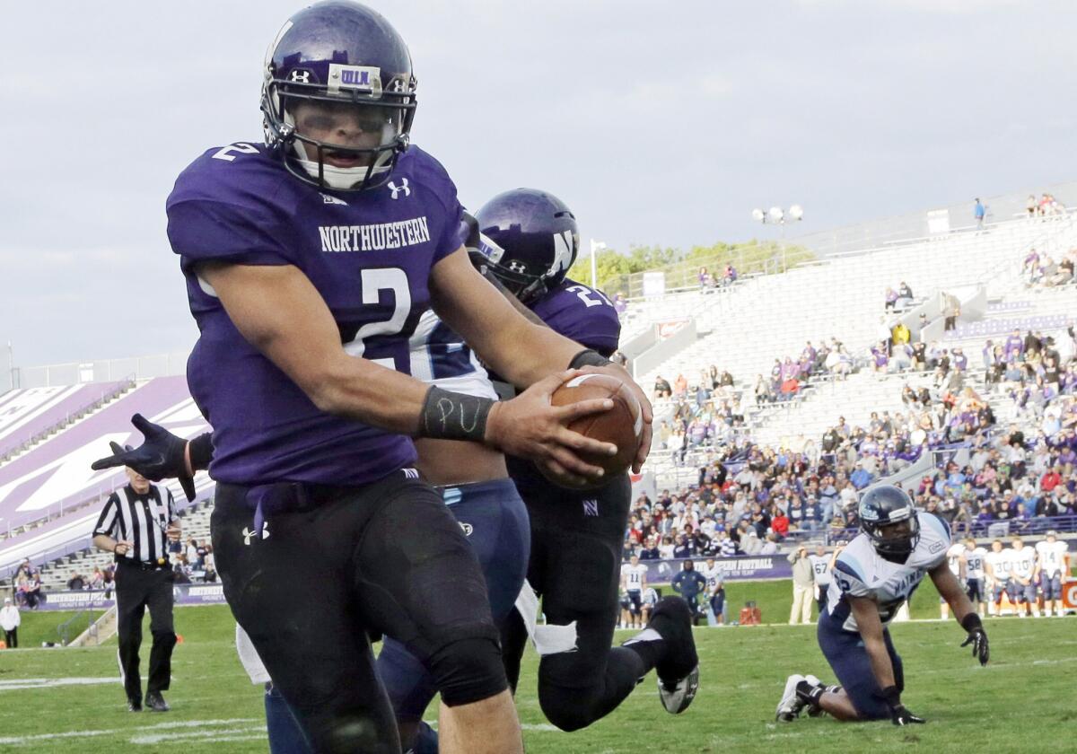 In this Sept. 21, 2013, file photo, Northwestern quarterback Kain Colter (2), wears APU for "All Players United" on wrist tape as he scores a touchdown during a game against Maine in Evanston, Ill. The decision to allow Northwestern football players to unionize raises an array of questions for college sports.