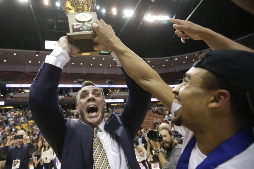 UC Irvine Coach Russell Turner holds up the Big West Conference tournament championship as he and his players celebrate the title and automatic NCAA tournament berth.