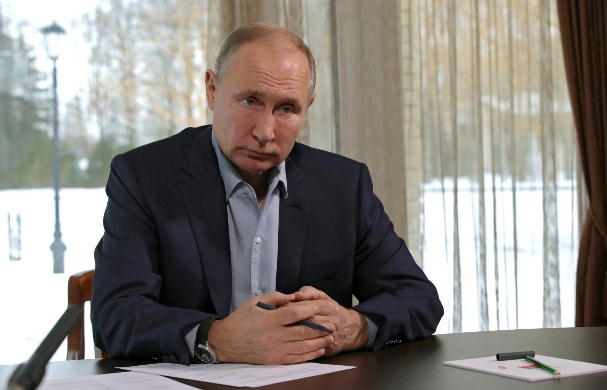 Russian President Vladimir Putin sits at a desk as part of a videoconference with students in January. 
