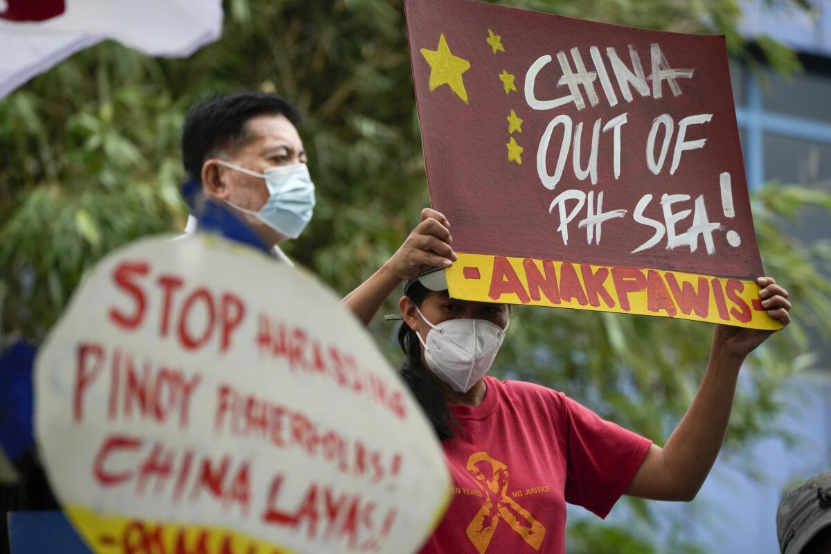 Activists hold slogans as they protest outside the Chinese consulate in Makati, Philippines on Wednesday, Nov. 24, 2021. The Philippine navy successfully transported food supplies to marines guarding a disputed shoal in the South China Sea on Tuesday, a week after China's coast guard used water cannons to force the supply boats to turn back, sparking outrage and warnings from Manila, officials said. (AP Photo/Aaron Favila)