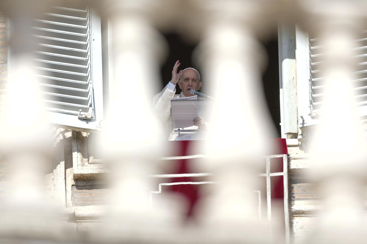 Pope Francis delivers his blessing from his window while holding a paper
