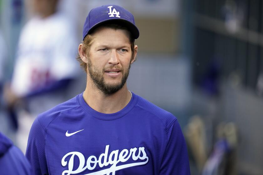Los Angeles Dodgers starting pitcher Clayton Kershaw walks in the dugout during a baseball game.