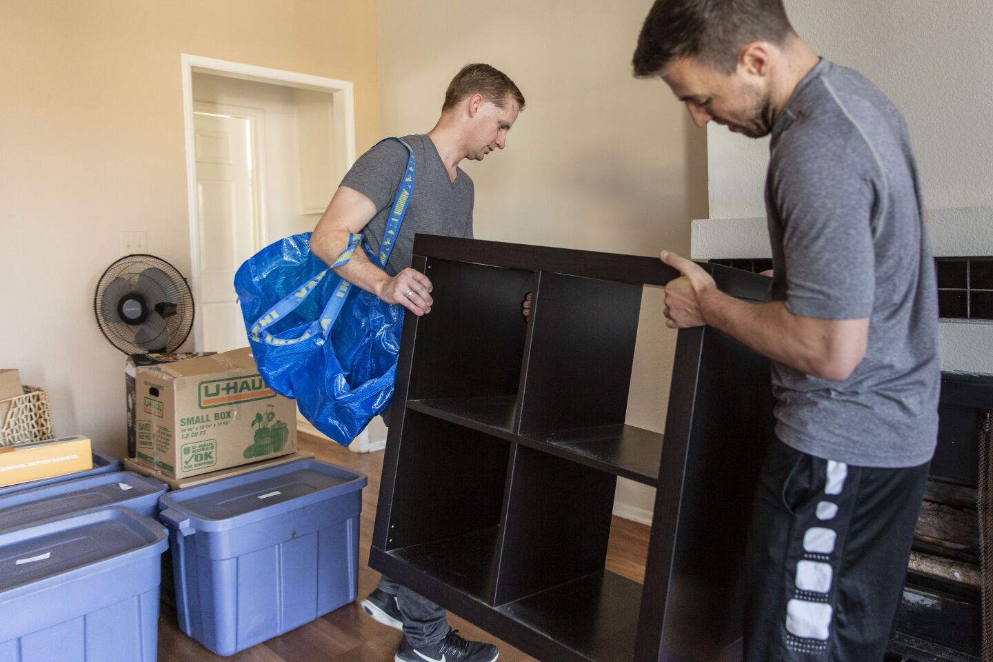 Warma and Dillon unpack furniture in Dillon’s new one-bedroom apartment.