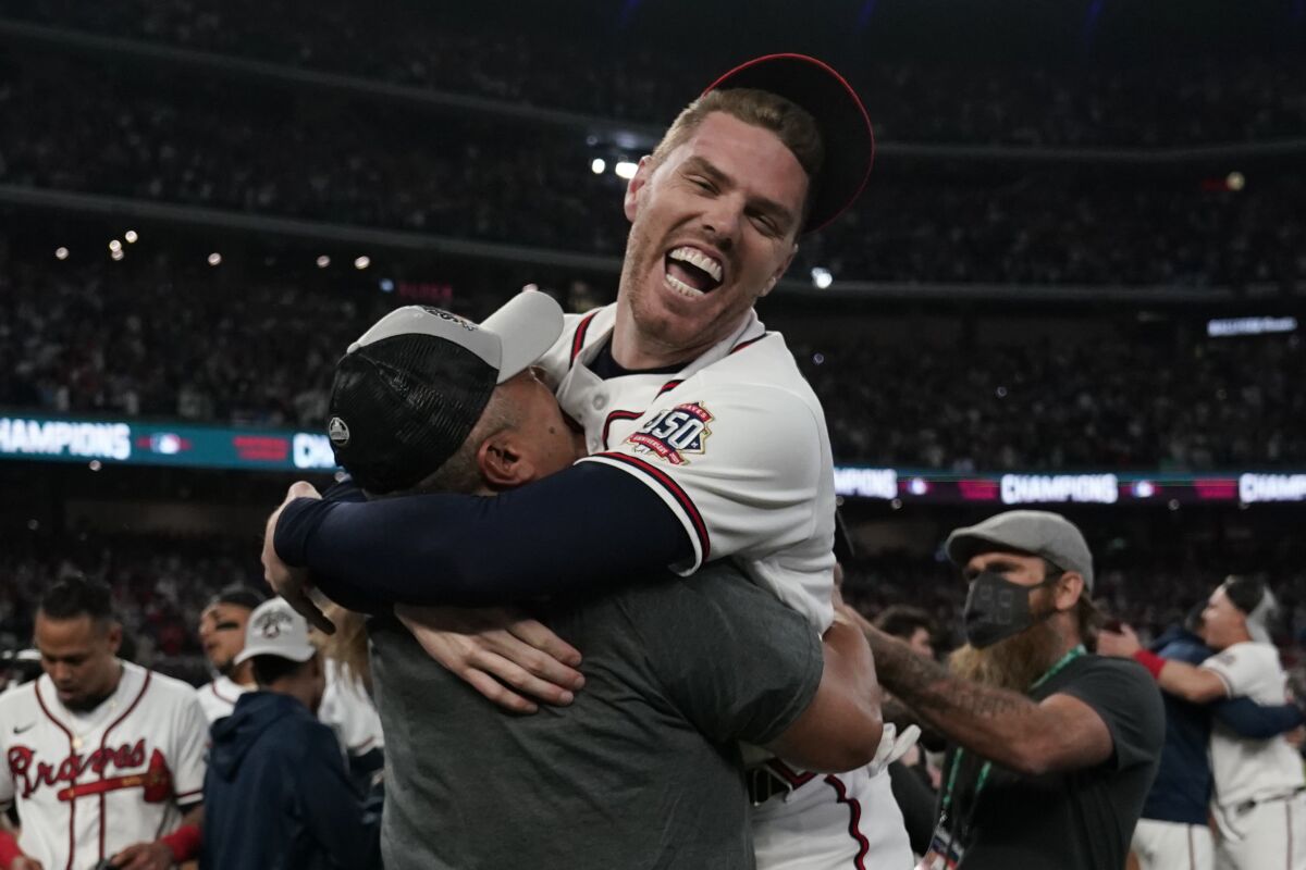 Braves first baseman Freddie Freeman is hugged by a coach after winning the NLCS against the Dodgers on Oct. 23, 2021.