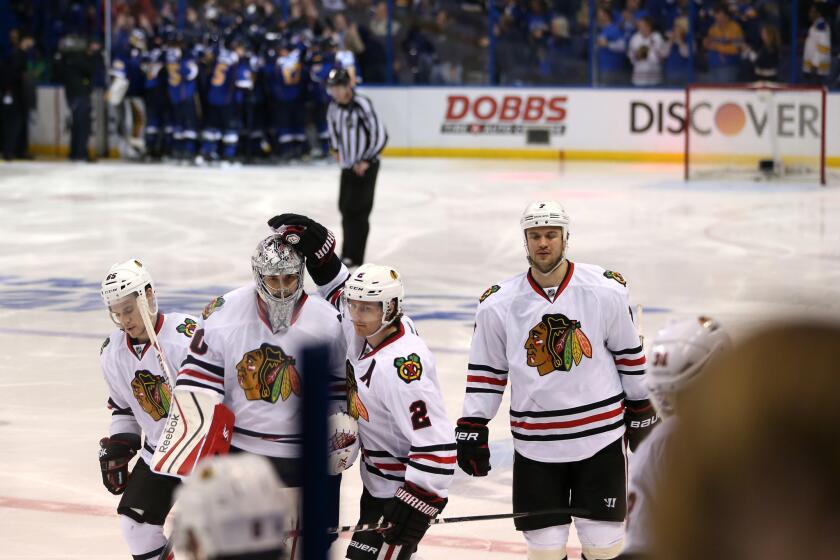 Blackhawks goalie Corey Crawford is consoled by Duncan Keith as the Blues celebrate their victory in triple overtime.
