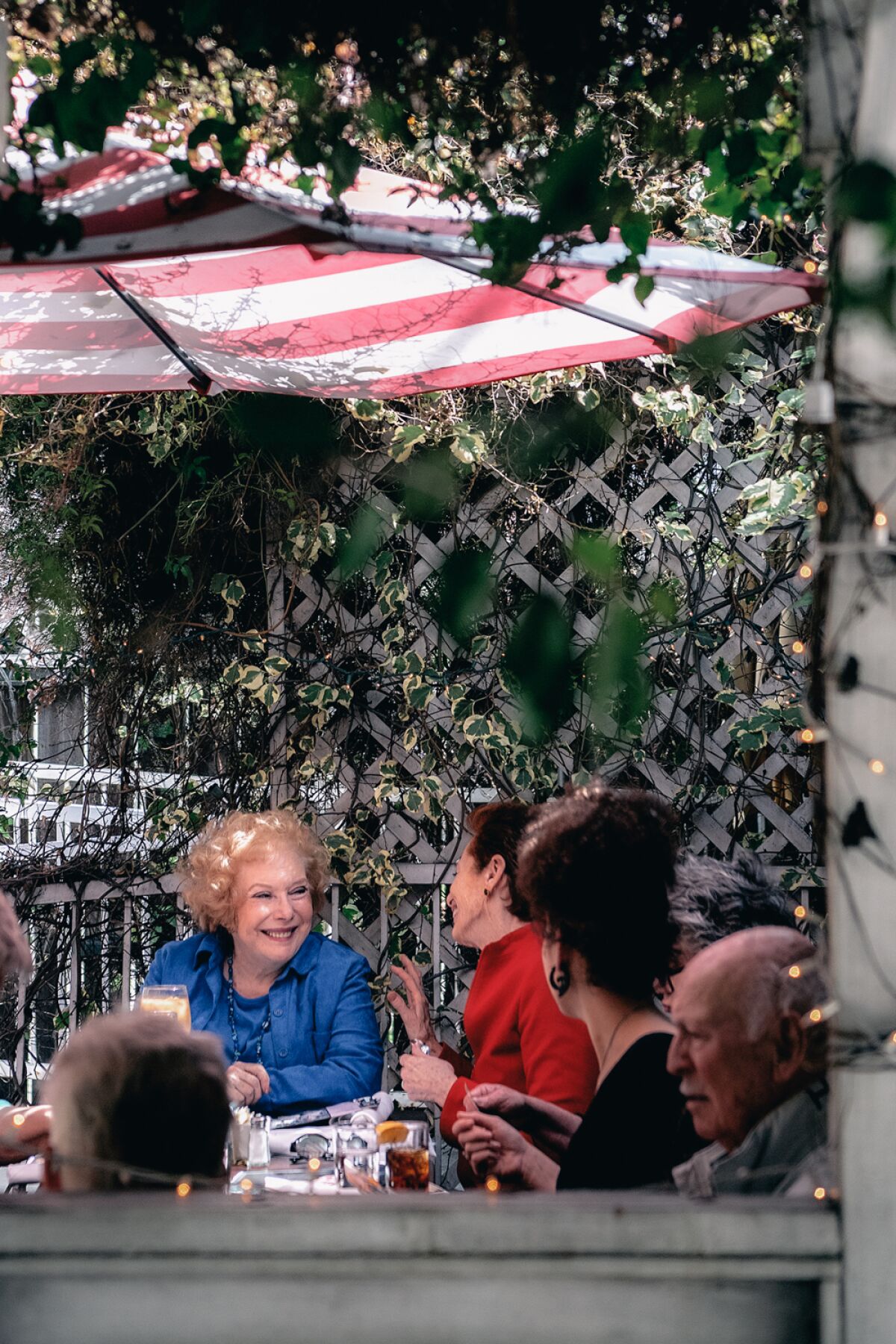 People dine on a terrace under umbrellas.