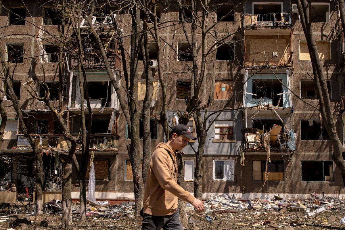 A man walks past a bombed-out building.