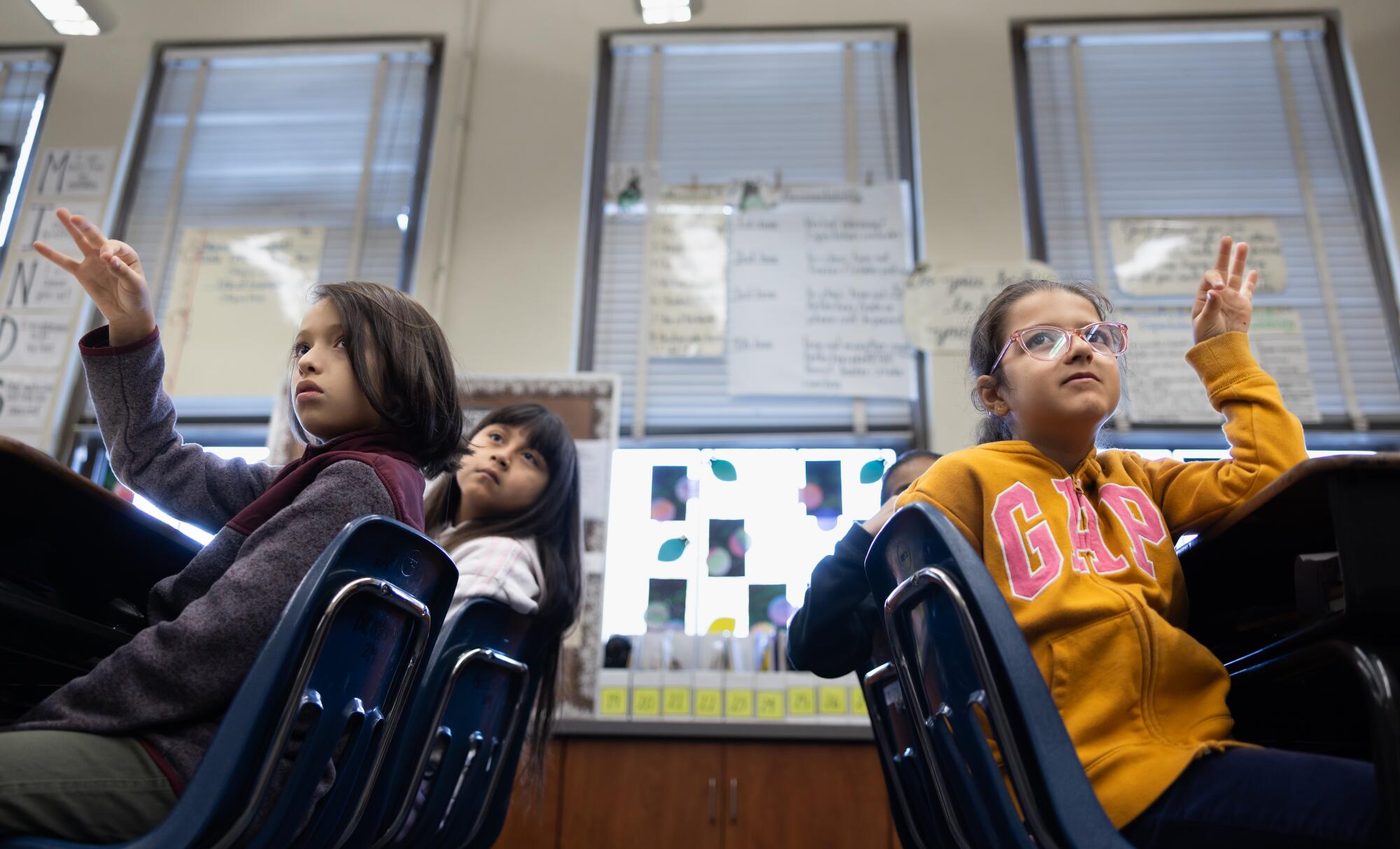 A group of fourth grade students sit at their desks.  