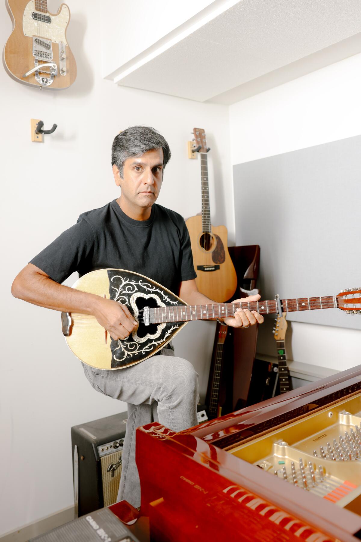 Siddhartha Khosla in his studio holding a string instrument.