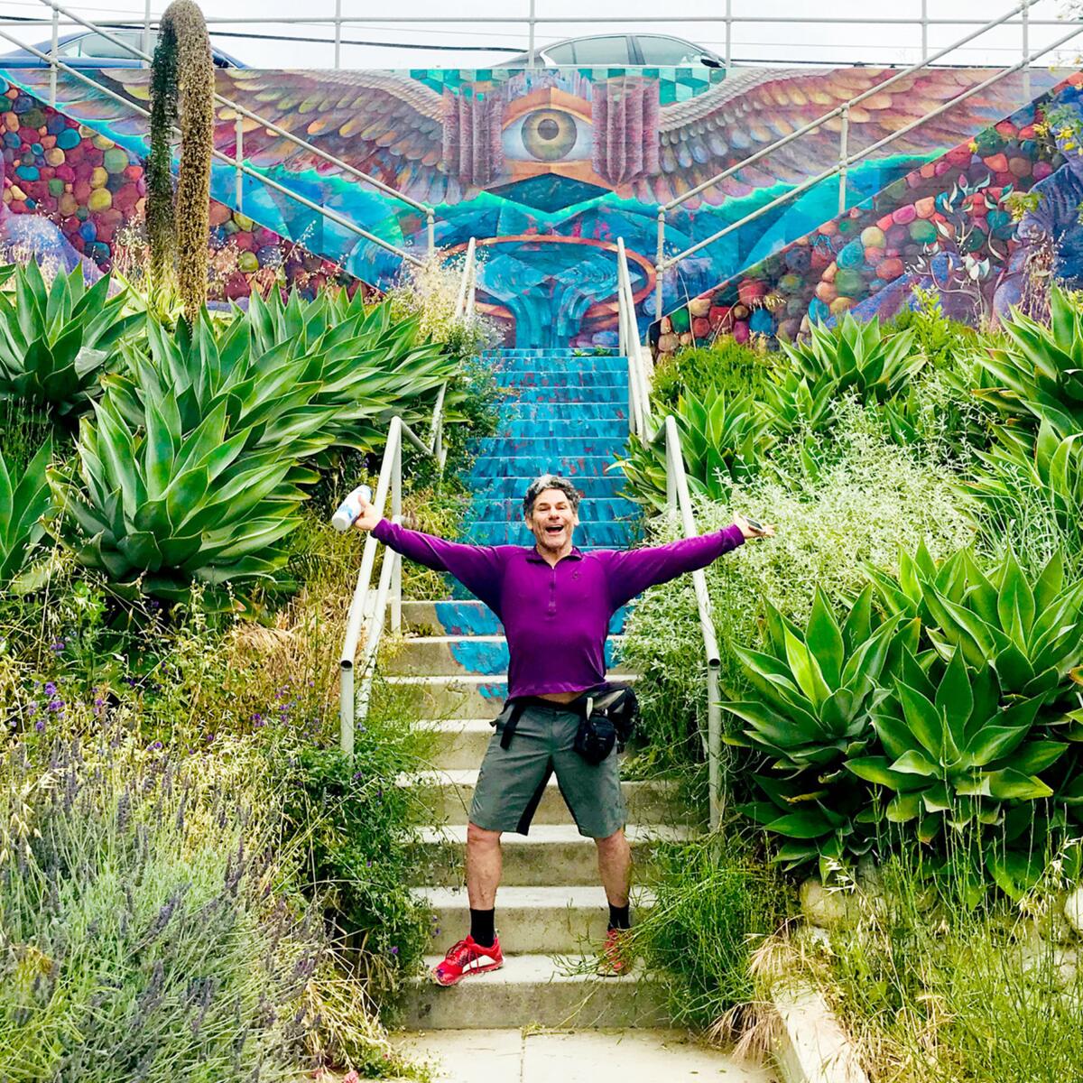 Roy Wallack stands in front of the "Fluid City Rising" mural by artist Ricardo Mendoza.