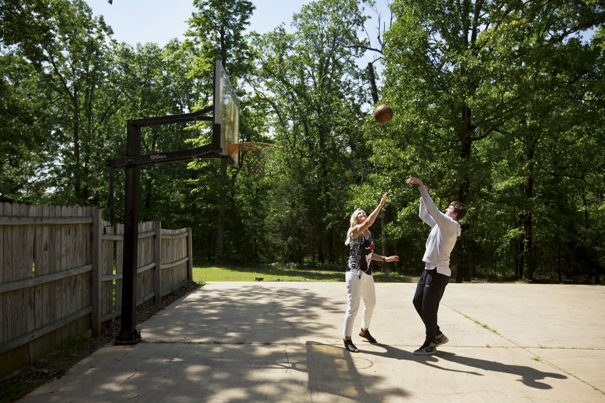 Austin Reaves shoots over his mother, Nicole Wilkett, on a half-court next to the family's house on a 300-acre farm.
