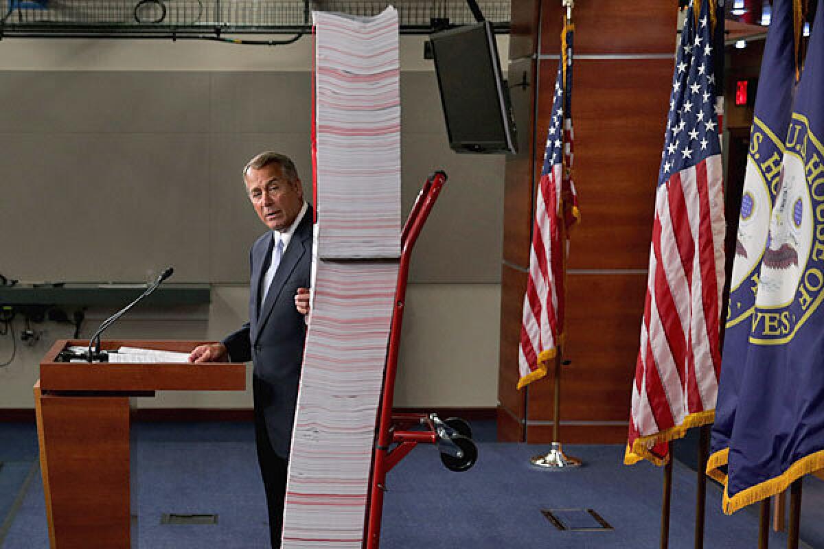 Speaker John Boehner (R-Ohio) next to a printed version of the Patient Protection and Affordable Care Act.