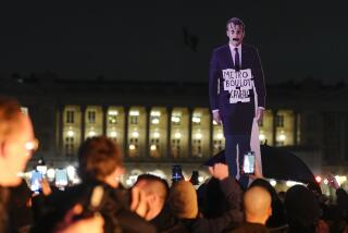Demonstrators hold a placard depicting French President Emmanuel Macron that reads, "metro, work, grave" during a protest in Paris, Friday, March 17, 2023. Protests against French President Emmanuel Macron's decision to force a bill raising the retirement age from 62 to 64 through parliament without a vote disrupted traffic, garbage collection and university campuses in Paris as opponents of the change maintained their resolve to get the government to back down. (AP Photo/Lewis Joly)
