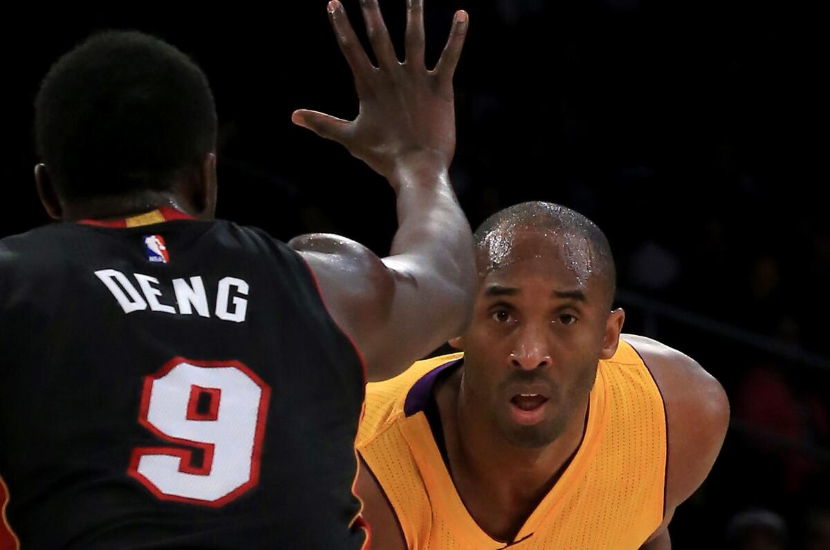 Kobe Bryant looks past the outstretched hand of Heat forward Luol Deng during the first quarter of a game Tuesday against Miami at Staples Center.