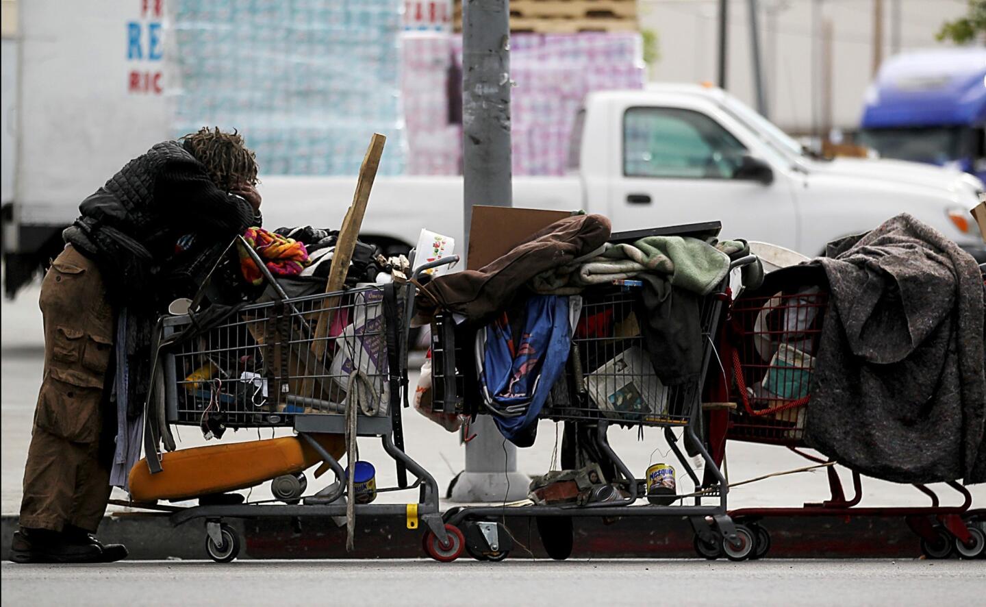 A man pulling a line of shopping carts pauses along 9th Street in downtown Los Angeles.