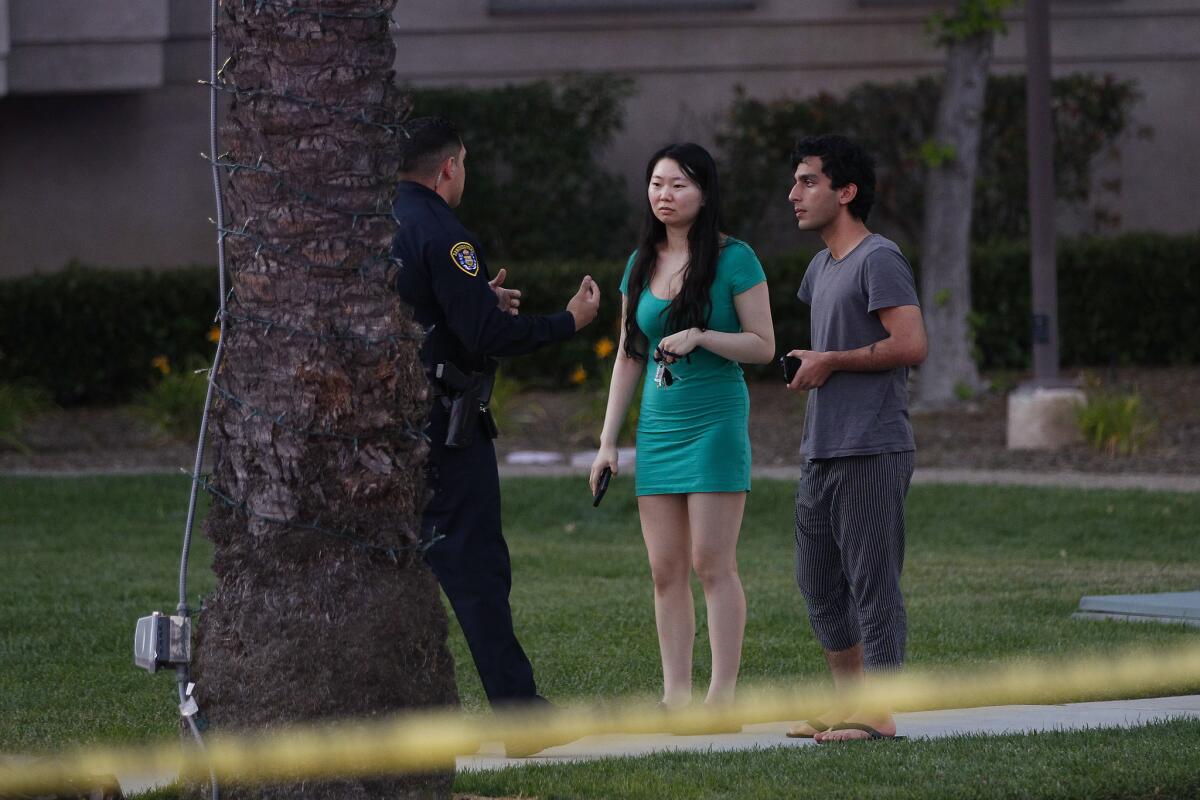 A San Diego police officer stops to question a couple near the area in La Jolla where a gunman is reported to have shot seven victims at an apartment complex. (Nelvin C. Cepeda / San Diego Union-Tribune)